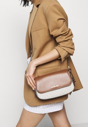 Michael Kors crossbody bag featuring a brown leather top flap and a beige fabric base with an MK logo pattern, silver hardware accents.