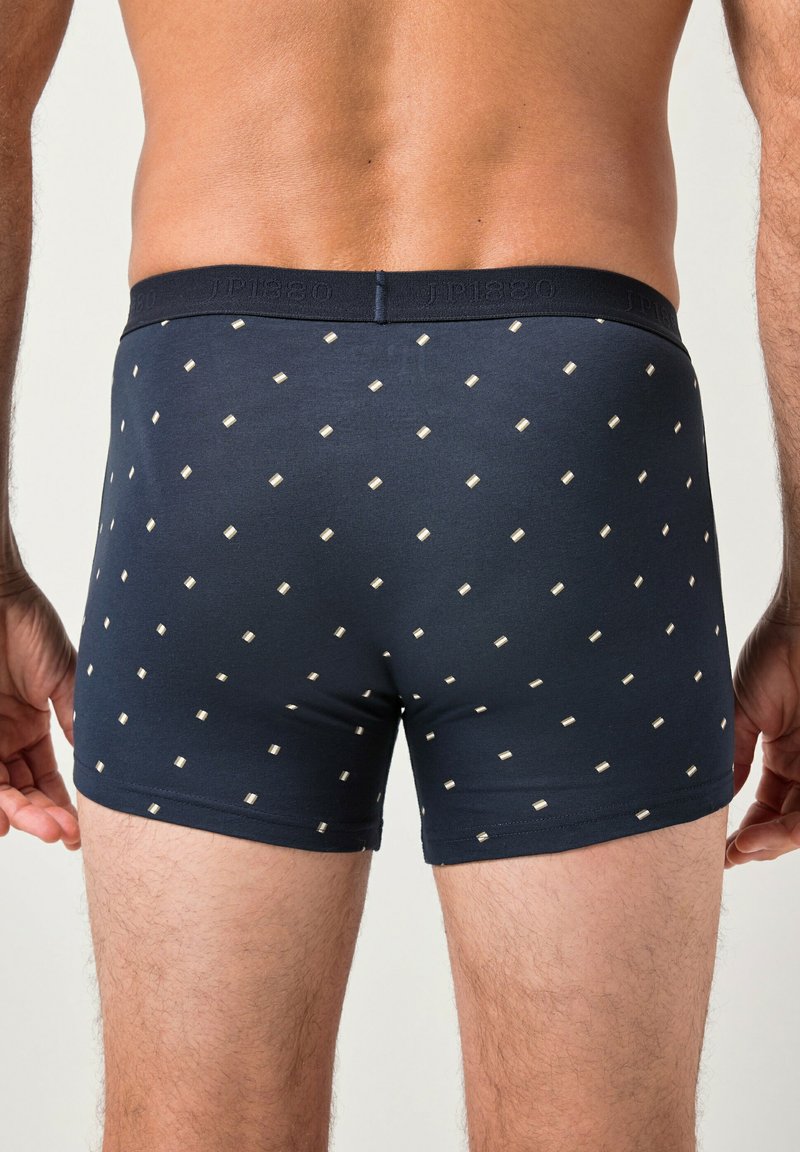 Boxer ajustados azul marino con un patrón de pequeños cuadrados color crema, que cuentan con una suave cinturilla elástica con detalle de logotipo grabado.
