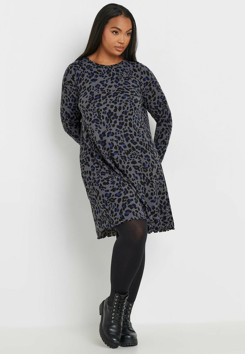 Leopardenmuster-Kleid in Grau-, Schwarz- und Blautönen, mit langen Ärmeln und lockerer Passform. Kombiniert mit schwarzen Schnürstiefeln und Strumpfhosen.