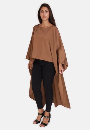 Brun satin kappe parret med sorte tætsiddende bukser og sorte sandaler. Kappen har et løst, svævende design og brede ærmer.