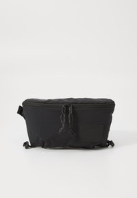 Black zippered bag made of soft fabric, featuring a quilted upper, adjustable drawstring closures, and a branded patch on the front.