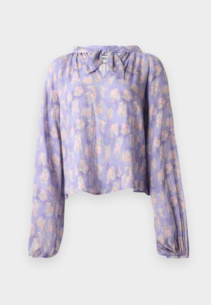 Ziedu blūze gaiši violetā audumā ar garām pūkainām piedurknēm un sasietu kakla izgriezumu. Iezīmēta ar maigu rozā un zaļo ziedu izdruku.