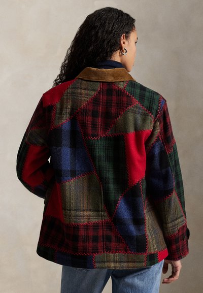 Chaqueta de cuadros parcheada con cuadrados rojos, verdes, azules y marrones, con costuras visibles, cuello de pana y un corte relajado.