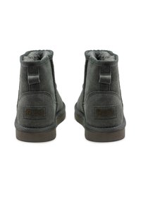 Szürke velúr bokacsizmák puha szőrme bélésse, lapos gumitalppal és varrott részletekkel. A külső oldalon, a sarok közelében található egy címke.