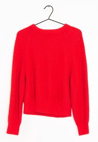 Roter Strickpullover mit langen Ärmeln, gerippter Textur, Rundhalsausschnitt und seitlichen Öffnungen am Saum. Hängt an einem schwarzen Haken vor einem weißen Hintergrund.