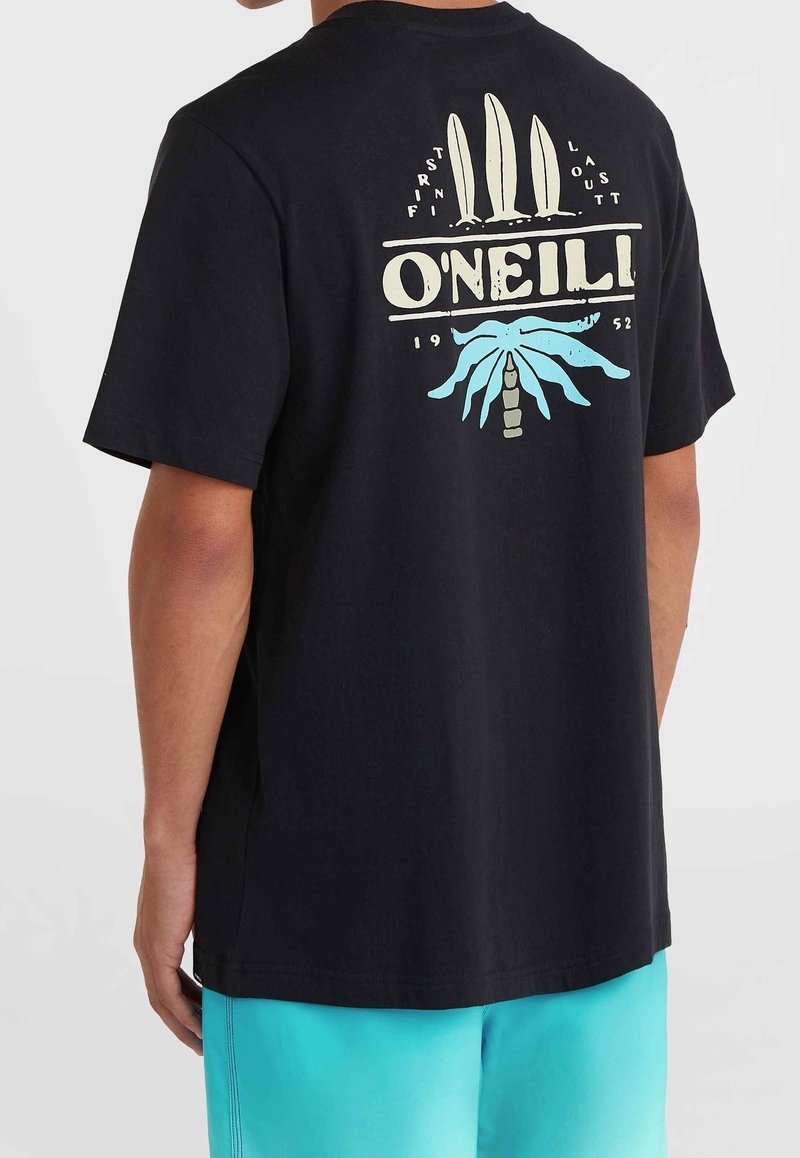 Mand iført sort T-shirt med cremet surfbræt og blå palmetræ-design samt "O’Neill 1952" tekst på ryggen, parret med turquoise shorts.