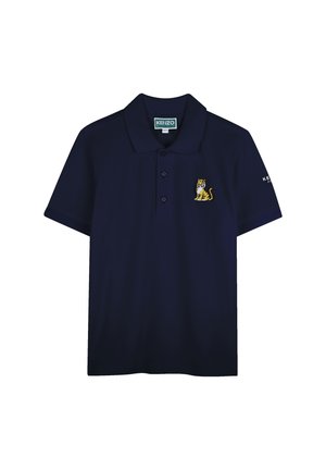 Polo bleu marine en tissu lisse, avec un logo de tigre brodé jaune et blanc sur la poitrine gauche et un texte de marque sur la manche.