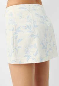 Květinová mini sukně ve světle žluté látce s modrým květinovým vzorem, rovného střihu a se zapínáním na zip na zadní straně.