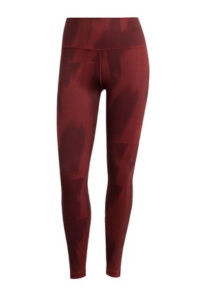 Red patterned leggings with high waistband, textured fabric, and fitted design. Features gradient abstract pattern and ribbed detailing.