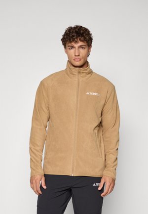 Beige fleece jacket with high collar, full zip, and side pockets. Features a white logo on the left chest and textured surface.