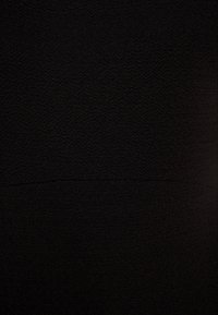 Tissu noir avec un motif texturé, arborant un design en zigzag subtil. La surface apparaît lisse et légèrement structurée.