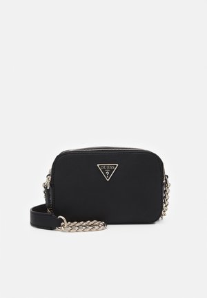 Sac bandoulière rectangulaire noir Guess avec une sangle chaîne argentée et un logo métallique triangulaire sur le devant, fermeture éclair sur le dessus.