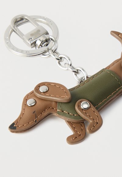 Μπρελόκ σε σχήμα Dachshund κατασκευασμένο από καφέ και πράσινο δέρμα, με μεταλλικές λεπτομέρειες, ραφές και κλιπ για στερέωση.