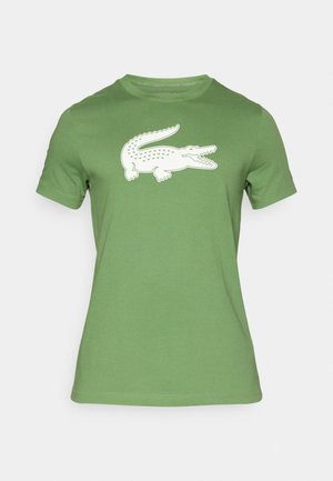 Green short-sleeve T-shirt made of cotton, featuring a white crocodile graphic printed on the front. Smooth texture, round neck design.