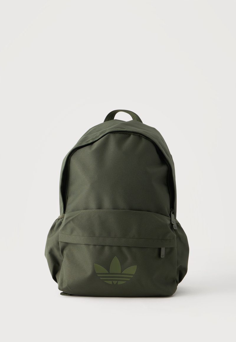 Sac à dos Adidas vert olive avec poche avant zippée et poignée supérieure, arborant le logo trèfle Adidas sur la poche frontale inférieure.