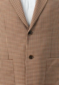 Braun und creme kariertes Blazer mit Reverskragen, Zwei-Knopf-Verschluss und aufgesetzten Taschen. Aus strukturiertem Stoff gefertigt.