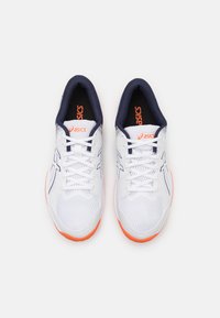 Hvite joggesko med marineblå krage, oransje detaljer, mesh-overdel og tradisjonelle snøringer. Har en strukturert såle for godt grep.