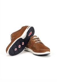 Zapatos de ante marrón con punta redonda, suela de goma blanca y detalles rojos en la suela exterior. Presentan un diseño con cordones y detalles de costura.