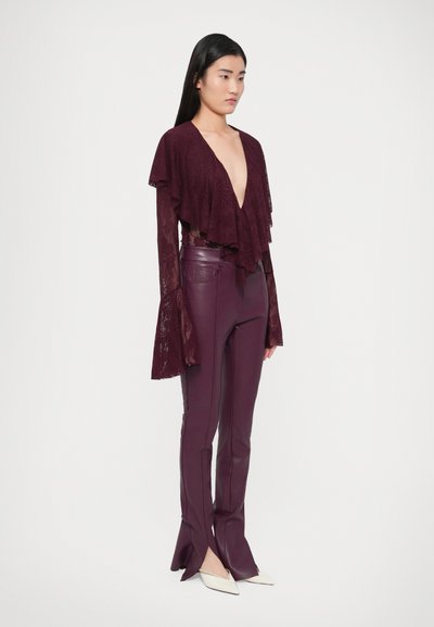 Bordó csipkés felső réteges fodrokkal és mély V-nyakkal, hozzá illeszkedő bőr nadrággal párosítva. Fehér hegyesorrú magas sarkúk egészítik ki az összhatást.