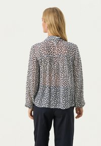 Durchsichtige Bluse mit langen Ärmeln und Kragen, mit einem navy- und weißen Blumenmuster, gerafftem Rücken und leicht lockerer Passform.