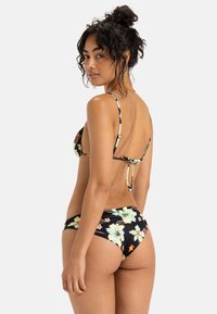 Zwarte bloemenbikini met lichtgroene en oranje bloemen; heeft dunne verstelbare bandjes, een lage rugontwerp en een onderkant met een gematigde bedekking.