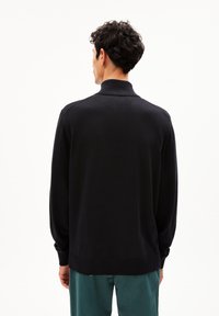 Zwarte gebreide sweater met een hoge kraag, geribbelde manchetten en zoom. Kenmerkt zich door een soepele textuur en een casual pasvorm, bekeken vanuit de achterkant.