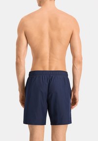 Bañador azul marino de tela ligera, con cintura elástica y diseño simple; visto desde la parte de atrás, mostrando una textura suave.