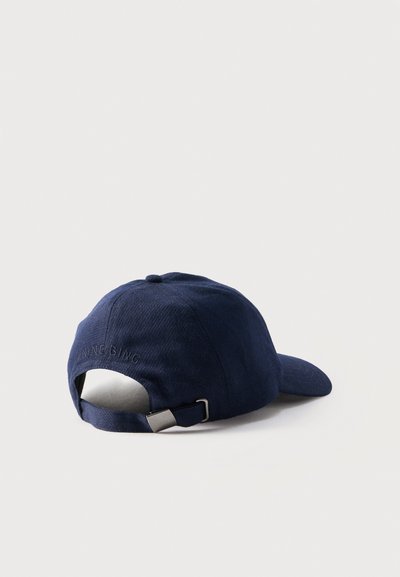 Berretto da baseball blu navy con cinturino regolabile e fibbia in metallo, testo ricamato sul retro, posizionato con la visiera rivolta a destra su una superficie bianca.