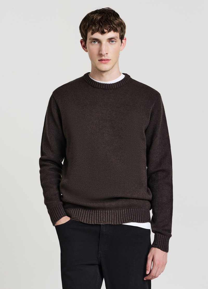 Brauner Strickpullover mit Rundhalsausschnitt, gerippten Bündchen und Saum. Wird über einem weißen Hemd getragen und zeichnet sich durch einen strukturierten Stoff in entspannter Passform aus.