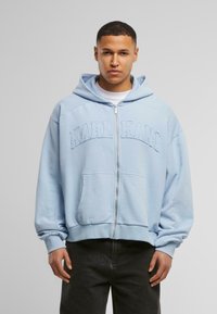 Lyseblå lynlås hoodie lavet af blødt stof, med en stor broderet "KARL KANI" på brystet og forlommer. Afslappet pasform.