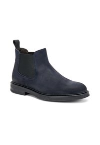 Bottines Chelsea en suède bleu marine avec des panneaux élastiques sur les côtés et une languette ; elles disposent d'une semelle noire plate et texturée pour la stabilité et l'adhérence.