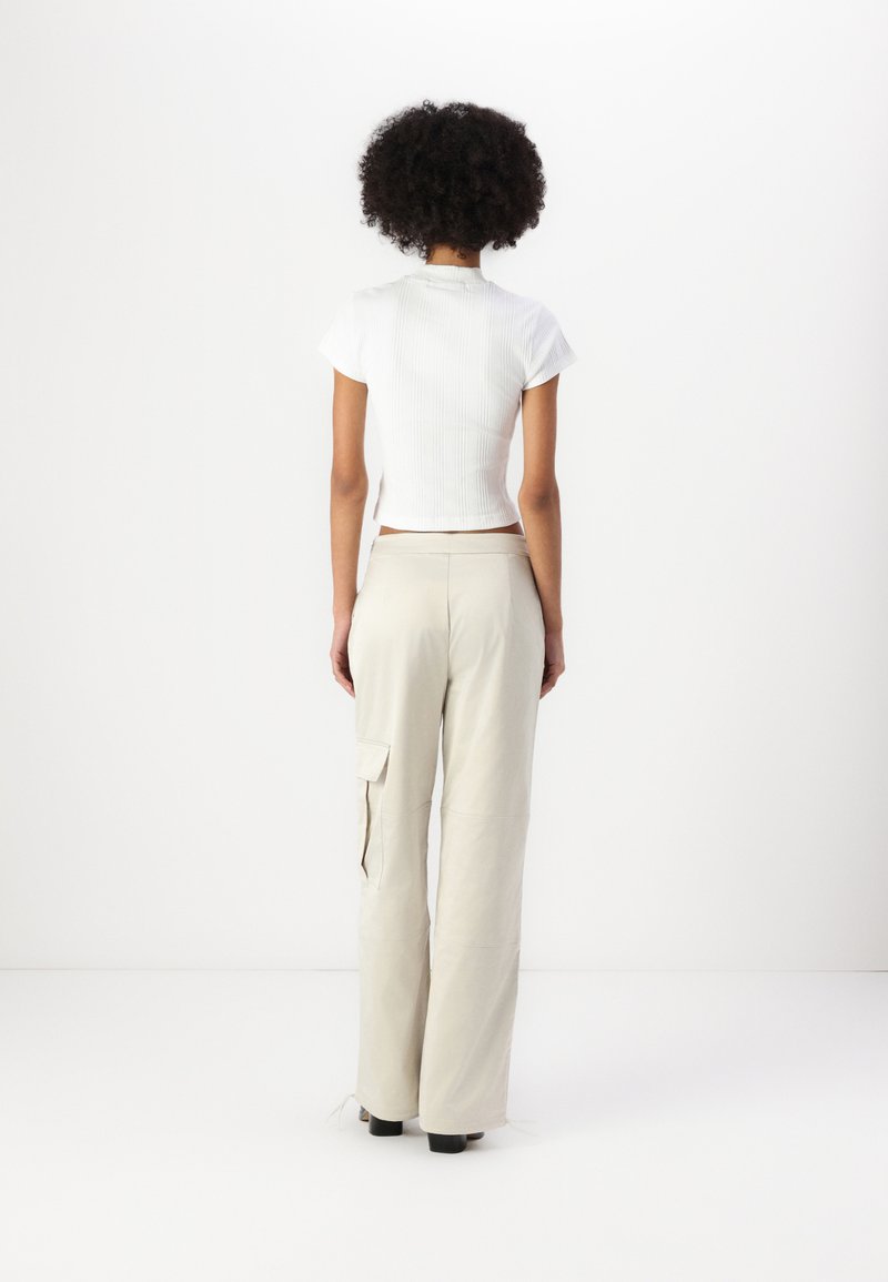 Witte geribbelde crop top met korte mouwen, gecombineerd met hoog gewaiste beige cargobroek met zijzakken. Glad textuur en losse pasvorm.