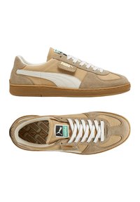 Beige Wildledersneaker mit weißen Lederakzenten, flachen weißen Schnürsenkeln und tanfarbenen Gummisohlen. Mit einem grünen und weißen Puma-Logo auf der Zunge.