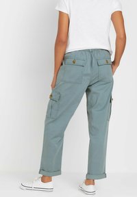 Lichtgroene cargobroek met opgerolde manchetten, voorzien van vier zakken en knoopsluitingen op de achterkant. Gemaakt van zacht, duurzaam materiaal.