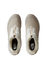 Lys beige sportsko med en glatt tekstur, glidelås og polstret design. Sålen er slank med en rund tå og logodetalj.