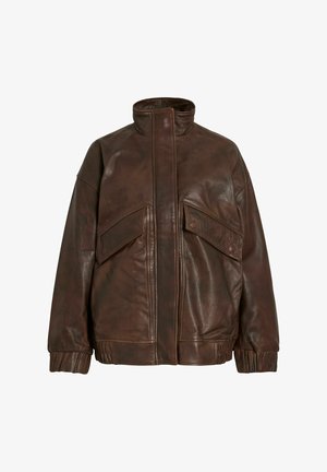 Giacca in pelle marrone con colletto alto, due grandi tasche con patta, polsini a costine e vestibilità rilassata. La pelle ha una finitura testurizzata.