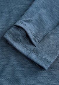 Material atletico de culoare albastră, arătând o manșetă pliată cu un model texturat și un finisaj neted, având cusături întărite pe margini.
