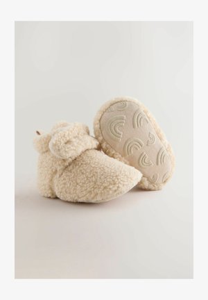 Flødefarvede, fluffy booties med en blød tekstur, der har et afrundet design og en mønstret gummisål med subtile regnbueaccenter.