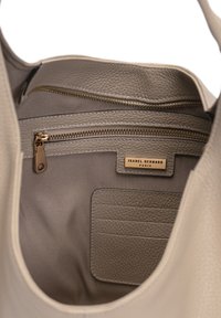Helles graues Leder-Shopper-Innenleben mit zwei Reißverschlusstaschen, einem Kartenfach und einem goldenen Logo-Tag. Weiche Textilauskleidung und glatte Textur.