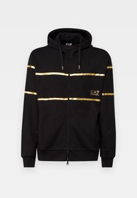 Black zip-up hoodie with gold stripe accents across the chest and a logo. Features a drawstring hood and ribbed cuffs. Soft fabric texture.