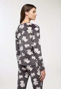 Set di pigiama grigio con motivo di orsetti in grigio chiaro e rosa. Tessuto morbido, maniche lunghe e pantaloni aderenti con elastico in vita.