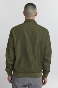 Olivgrüne Bomberjacke mit glatter Oberfläche, elastischen Bündchen und Saum sowie Stehkragen, von hinten betrachtet.