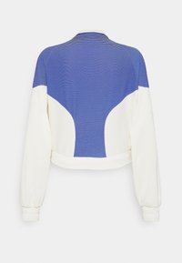 Korte jakke med blåstribet øverste sektion og hvid nederste sektion. Har elastiske ærmegab og glat tekstur. Enkel design.