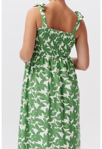 Grön och vit blommönstrad klänning med smockad livdel, justerbara band och en flödande kjoldesign.