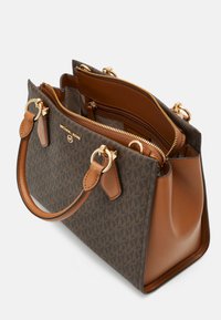 Brun monogrammeret tote taske med lysebrune læderdetaljer, dobbelthåndtag, lynlåslommer og hardware i guldfarve. Standard rektangulær form.