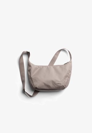 Sac bandoulière Bellroy marron clair avec sangle réglable et fermeture éclair, posé à plat sur fond blanc.
