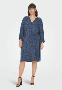 Robe bleue avec un motif floral rouge et marine, dotée d'un décolleté en V, de longues manches, d'une ceinture à la taille et d'un ourlet au niveau des genoux. Tissu doux au toucher.