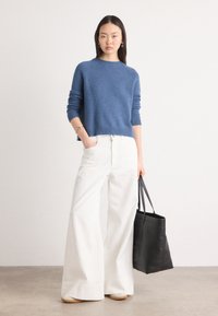 Blauwe gebreide trui met geribbelde randen, gecombineerd met witte wijde broek en een zwarte schoudertas. Strakke, casual look met gestructureerde materialen.