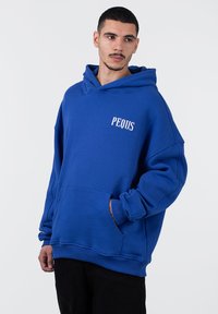Felpa blu con grande tasca frontale, polsini a costine e logo "PEQUS" stampato sul petto. Realizzata in tessuto testurizzato.