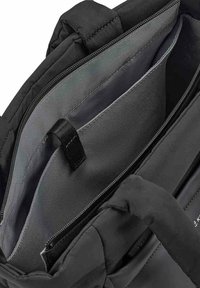 Musta laukun sisustus, jossa on sileä kangas, useita lokeroita, vetoketjullinen osio ja kestävä kahva kantamista varten.